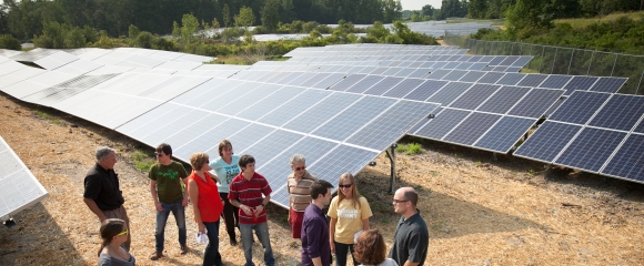 Group listens to lecture next to a solar array owned by Cornell