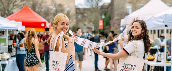 Students smiling at the farmers market on campus
