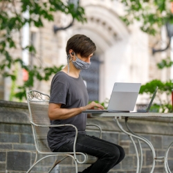 a student wearing a mask while on her computer 