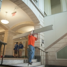 An employee carrying a beam through Warren Hall