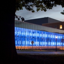 The windows of Stocking Hall facing Tower Road lit up by blue lights in the evening.